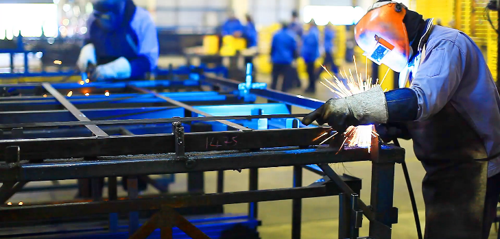 Welders welding a metal structure together inside a manufacturing facility image.